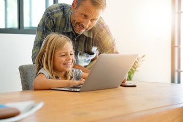 Daddy with little girl using laptop at home