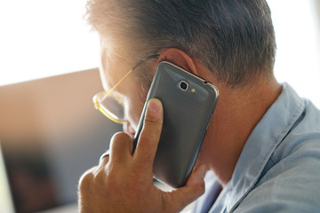 Closeup of mature man holding smartphone to ear - obrazy, fototapety, plakaty