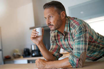 Fototapeta na wymiar Mature man drinking coffee in home kitchen