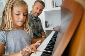 Little girl with teacher playing piano