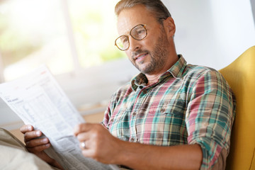 Mature man with eyeglasses reading newspaper