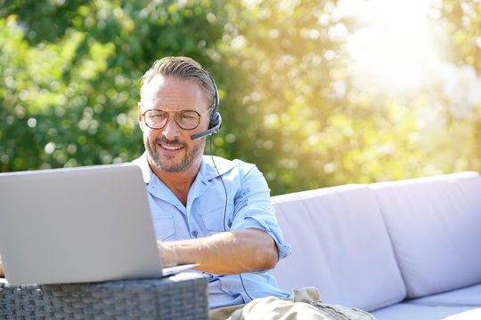 Cool businessman working with laptop and headset outside the office - Powered by Adobe