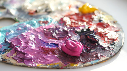 artist blends dark colors on the palette with a brush.