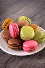 a plate of colorful macaroons on a wooden background