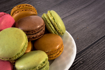 a plate of colorful macaroons on a wooden background