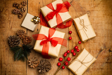 Paquetes de regalo de Navidad sobre mesa rústica de madera con piña y rama de acebo. Vista...