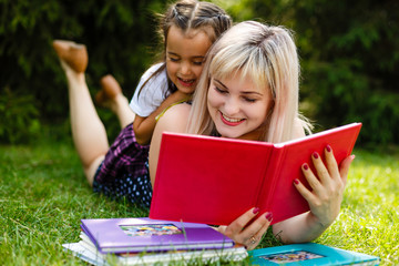 Mother and daughter reading a book at the park.