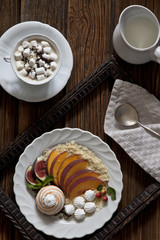 Fruit, biscuit and meringue, a cup of coffee with marshmallow on a vintage wooden table. Background, top view