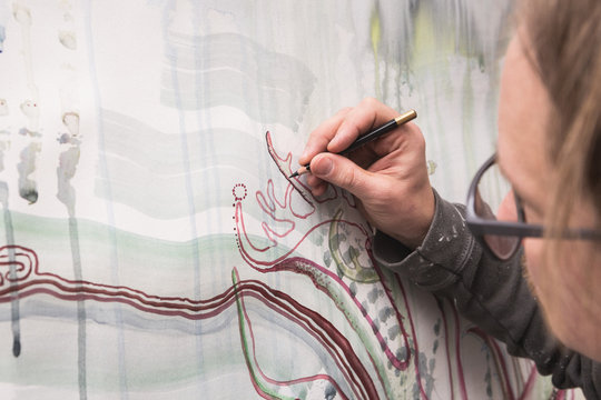 Artist is working with a pensil on his art piece in his work shop