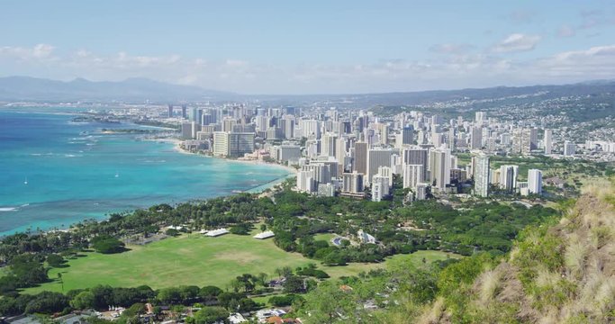 Buildings in Honolulu city and Waikiki Beach against sky during sunny day. Cityscape and sea are seen from Diamond Head State Monument. Famous landmark in Oahu.
