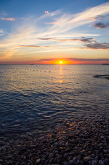 Amazing sea sunset on the pebble beach, the sun, waves, clouds