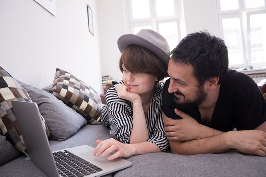 Young couple relax on the couch in front of the computer