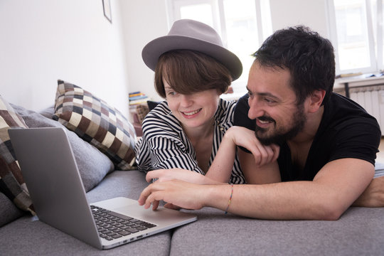 Young couple relax on the couch in front of the computer