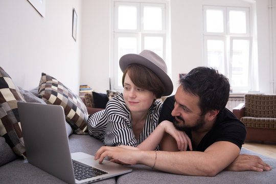 Young couple relax on the couch in front of the computer