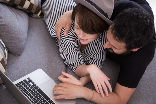 Young couple relax on the couch in front of the computer