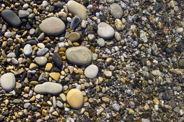 sea pebble beach with multicoloured stones, waves with foam