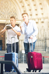 two happy male travellers making photo with digital camera and mobile phone