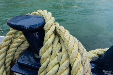 Closeup of an old yellow frayed boat rope, water background with landscape