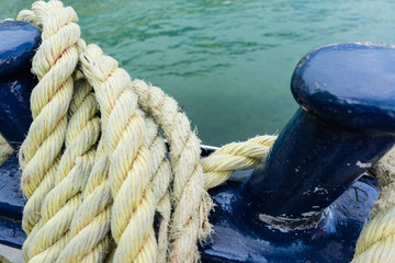 Closeup of an old yellow frayed boat rope, water background with landscape