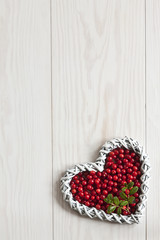  Fresh red forest cowberry in the shape of heart on a white wooden background. Concept for Christmas, Valentine's Day. Background, space for text, copy space