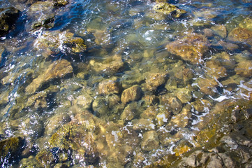 rocky sea shore with pebble beach, waves with foam