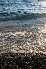 sea pebble beach with multicoloured stones, waves with foam