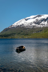 The Norwegian landscape with a boat on lake against mountains.