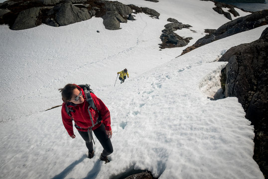 Hiking in difficulty snowy terrain in a Norway during a sunny summer day.