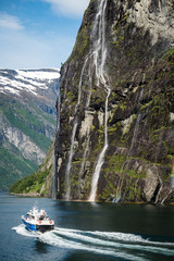Obraz premium Cruise boat at the famous geiranger fjord waterfalls in norway.