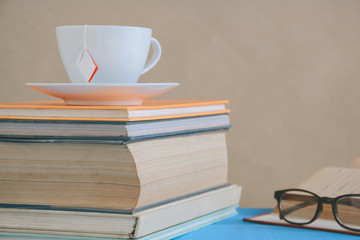Fototapeta premium Book glasses and tea on the desk with study and education concept