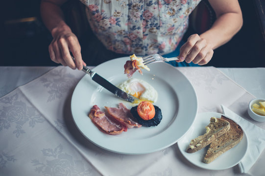 Woman having breakfast of eggs and bacon