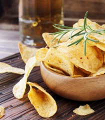 Chips in a wooden bowl and beer