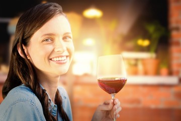 Composite image of smiling woman holding a glass of red wine
