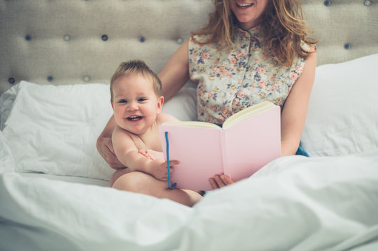 Young mother in bed reading to her little baby