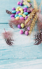 Easter colored eggs, feathers, blue wooden