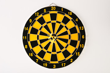 Three yellow darts in bullseye on dartboard