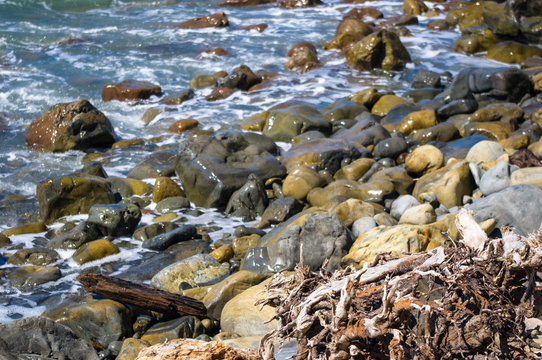 Fototapeta rocky sea shore with pebble beach, waves with foam