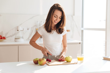 Happy healthy woman cutting fruits on a wooden board