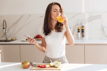 Young joyful woman drinking orange juice