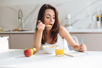 Casual young woman eating corn flakes cereal for breakfast