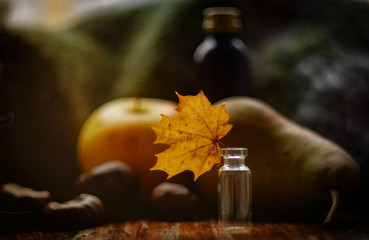  Autumn concept retro image with chestnuts, apple, pear and single maple leaf into small bottle. Selective focus.