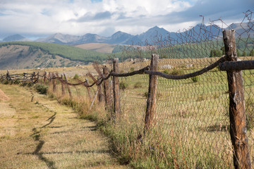 Obraz premium Wooden fence in the highlands and sky with clouds