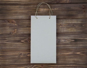 Beige paper bag with handles on brown wooden background.