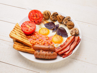 Full English Breakfast including sausages, grilled tomatoes and mushrooms, egg, bacon, baked beans, bread with orange juice