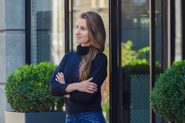 Stylish, slender, confident woman stands on the city street in black sweater,