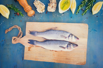 fresh sea fish preparation - top view of two seabass fish on cutting board, retro toned