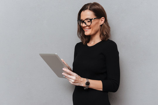Side view of smiling business woman in eyeglasses using computer