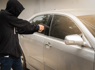 Fototapeta na wymiar Terrorist bandit thief a car ,pointing a gun at the driver car owner