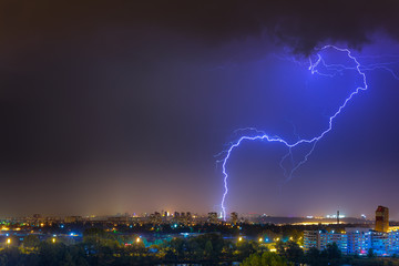 Naklejka na ściany i meble Lightning over the city at the summer storm. Dramatic, breathtaking atmospheric natural phenomenon.