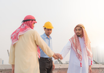 Fototapeta premium Successful two Young Arabic business people and engineer are joining their hands together in building site. selective focus on hands,business and teamwork of project successful